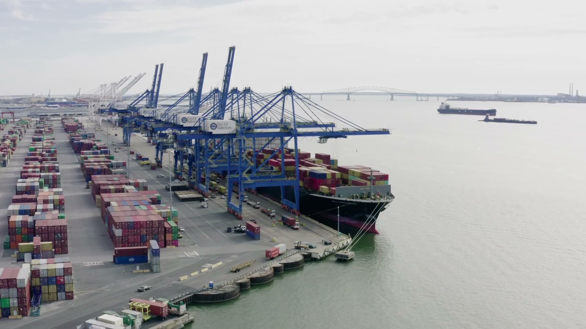 Gantry cranes working a container ship at a terminal (licensed stock footage)